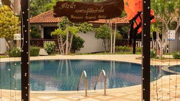 Zona de piscina en un resort con un arco de madera con el letrero 'Resort Guest Only' y un cartel en un idioma extranjero.