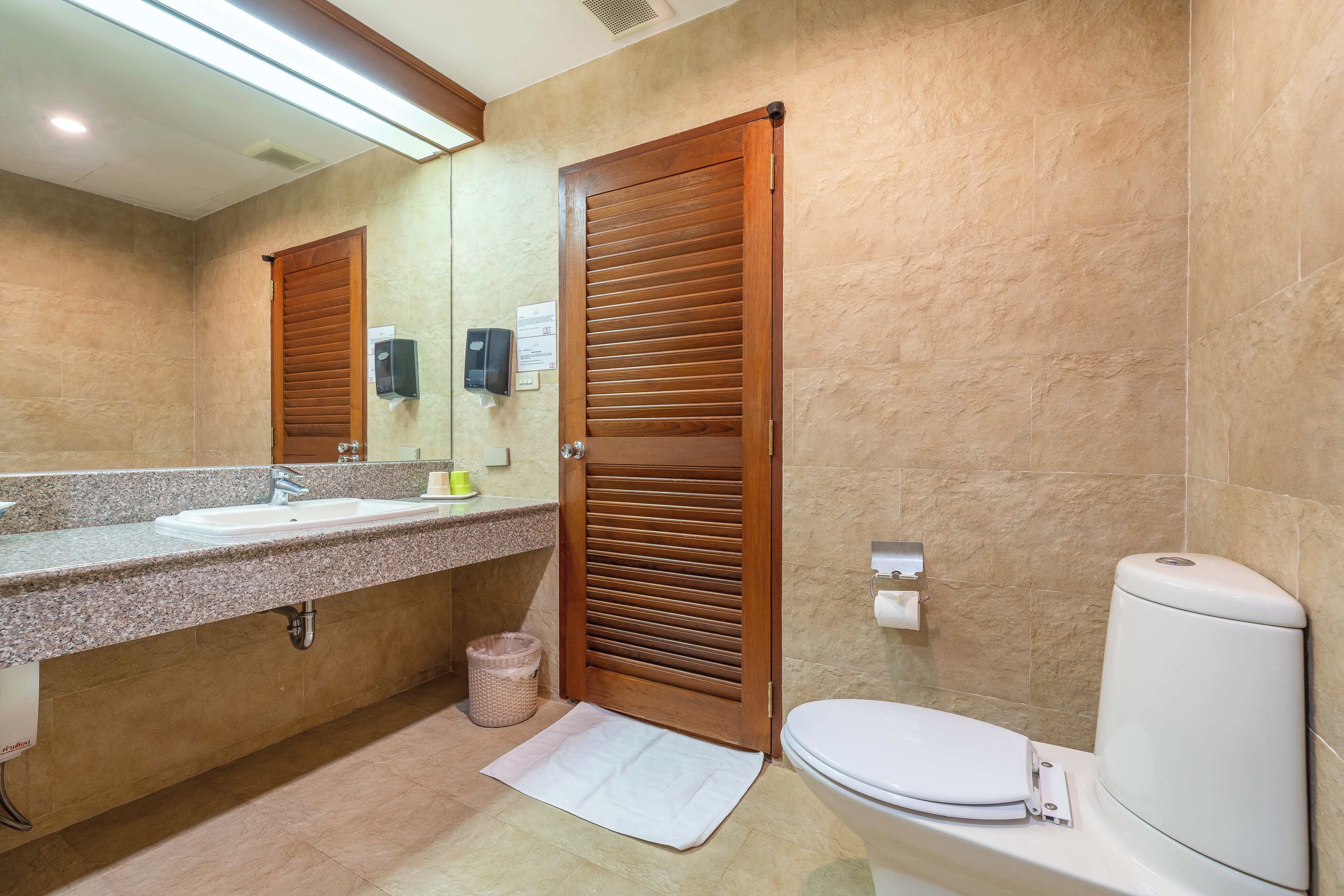 Un baño con lavabo, espejo, inodoro y puerta de madera.
