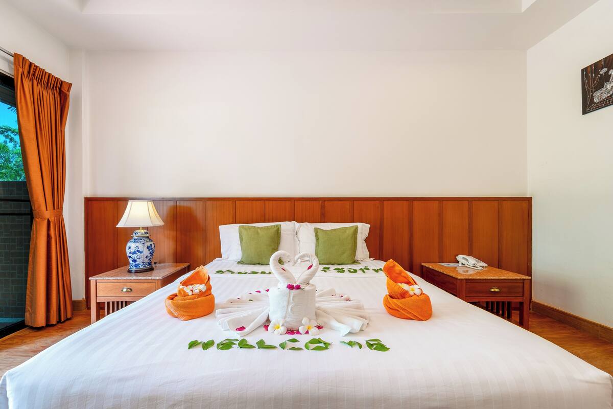 A hotel room with a neatly made bed, a lamp on a bedside table, and a telephone on another table.