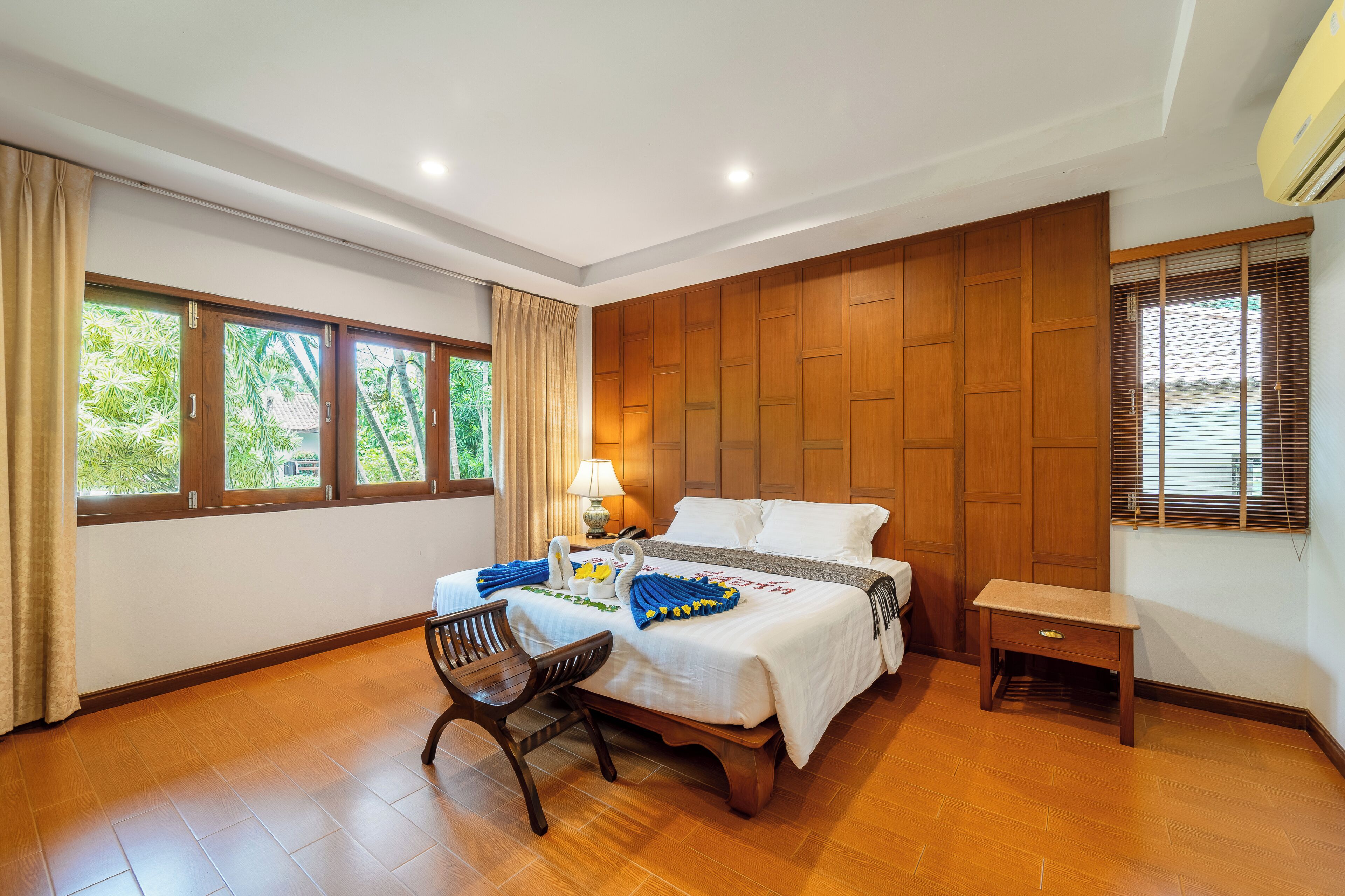 Une chambre d’hôtel avec un lit, un bureau, une chaise, une lampe et une fenêtre avec des rideaux.