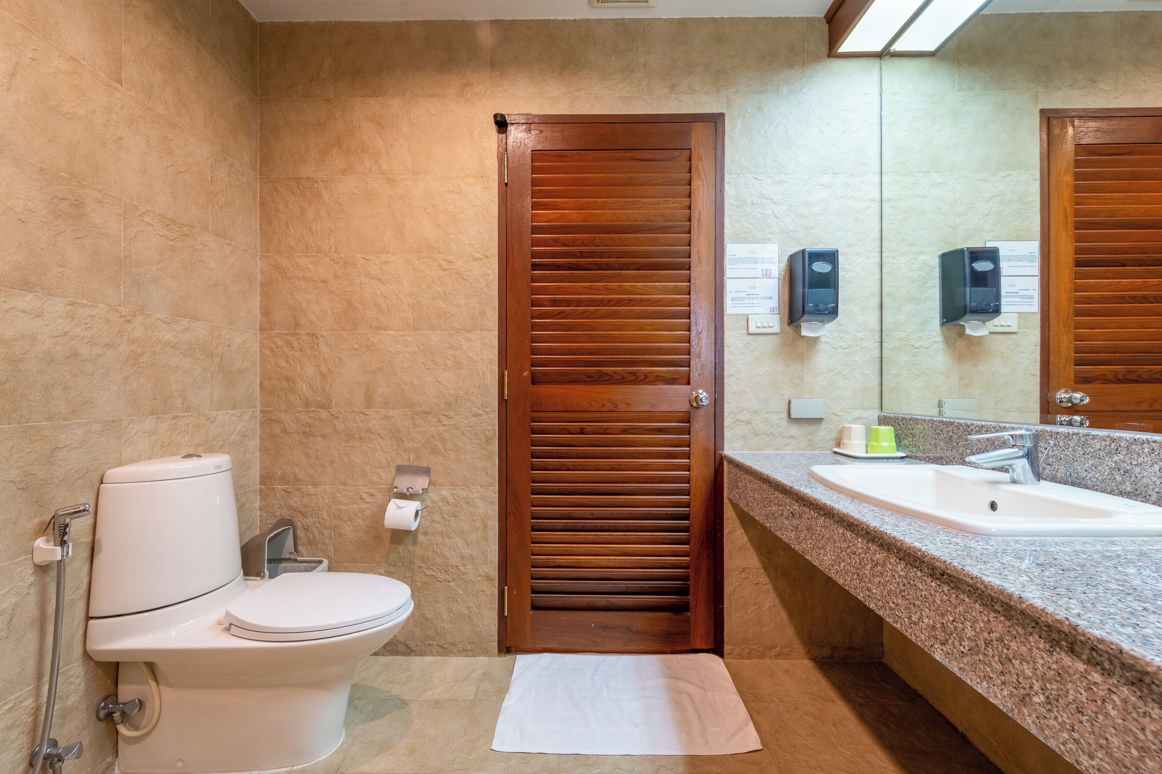 Un baño con inodoro, lavamanos y puerta de madera.
