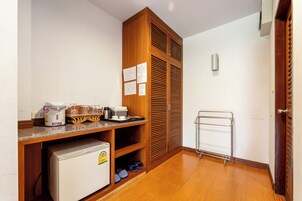 Una kitchenette compacta con refrigerador, cafetera y un panera sobre la encimera.