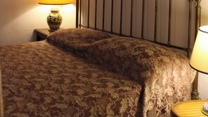 Un dormitorio con cama, mesita de noche, lámpara y cabecero de madera.