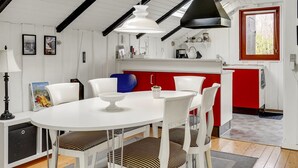 Une cuisine moderne aux couleurs rouge et blanche, dotée d’un puits de lumière et d’un coin repas avec des chaises blanches et une table blanche.
