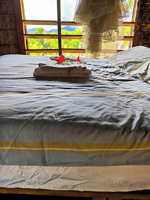Un lit avec un drap blanc et une serviette pliée ornée de fleurs rouges.
