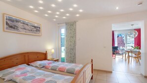 Une chambre avec deux lits, une fenêtre, une porte donnant sur un balcon et un coin repas.