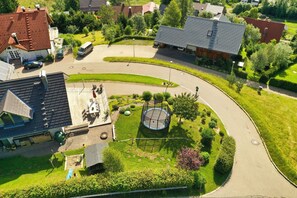 Vue aérienne d’un quartier résidentiel avec des maisons, un rond-point et un trampoline dans une cour.