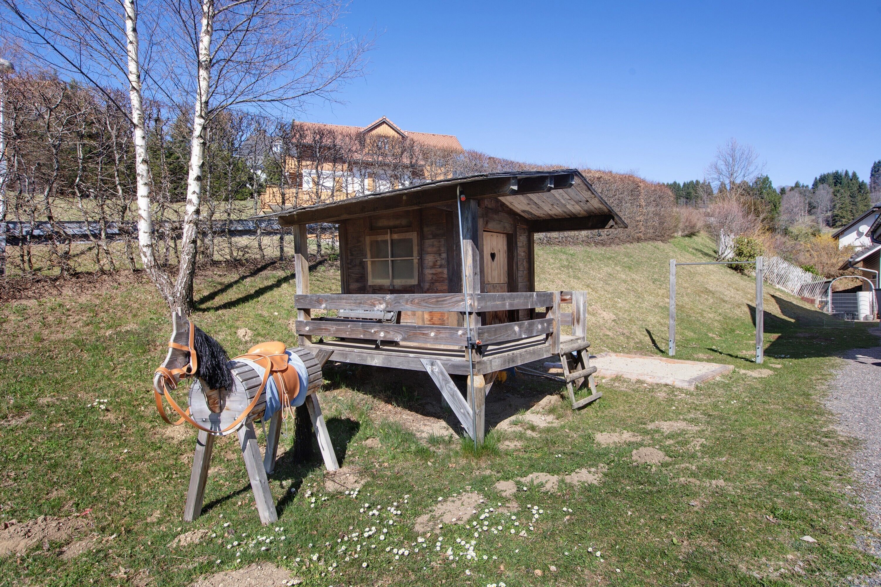 Eine Holzhütte mit geneigtem Dach, einer Holzterrasse und einer kleinen Veranda.