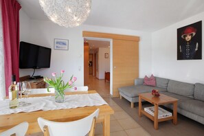 A living room with a television, a sofa, a coffee table, and a dining area with a table and chairs.