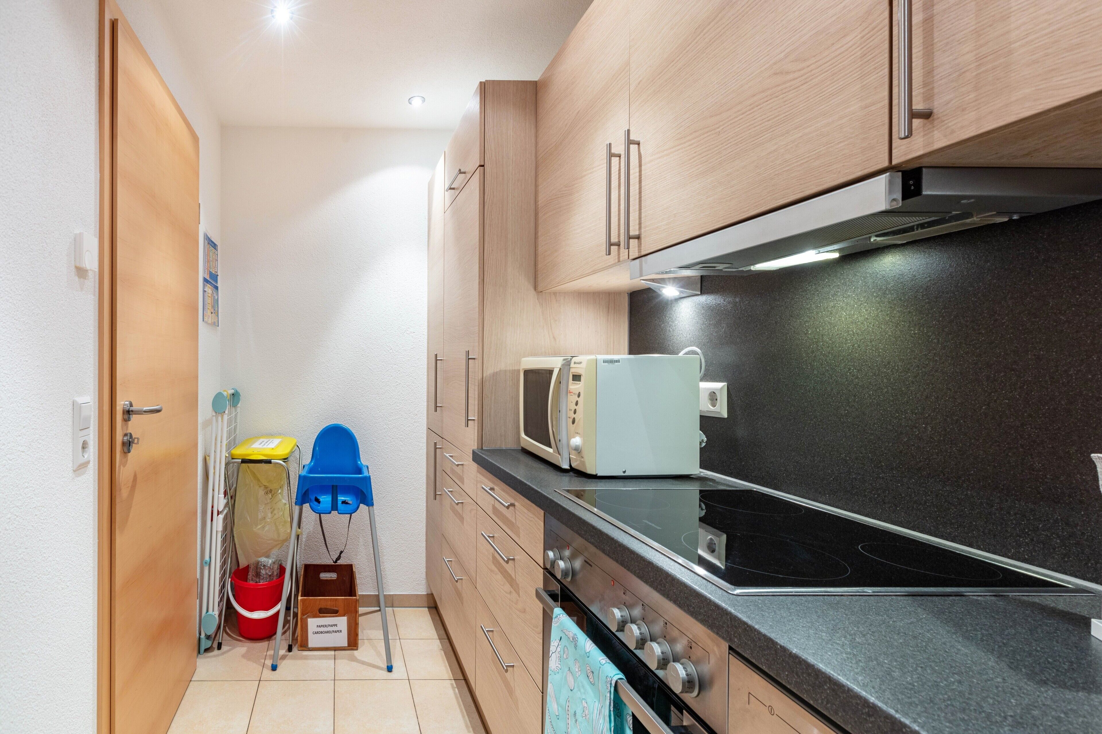 Une cuisine de taille réduite, dotée de meubles en bois, d’un four à micro-ondes et d’une cuisinière.