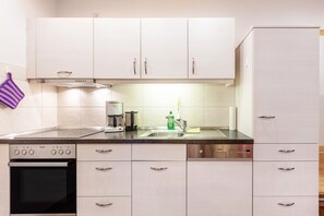 A modern kitchen with white cabinets, stainless steel appliances, and a purple towel hanging on the wall. - Apartment 'Feldberg' with French balcony and Wi-Fi (Todtnau)