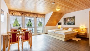 Un dormitorio con techo de madera, una cama, mesitas de noche y una ventana con cortinas.