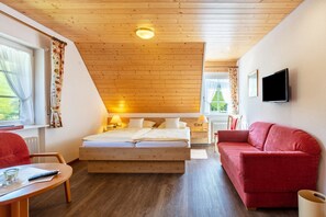 A bedroom with a wooden ceiling, a bed, a red sofa, a TV, and a window with curtains. - Apartment 'Stübenwasen' with Balcony and Wi-Fi (Todtnau)