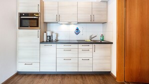 Una cocina moderna con gabinetes de madera, horno empotrado y pileta de acero inoxidable.