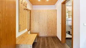 Un interior de madera con un banco, un armario de madera y una puerta de vidrio que da a un baño.