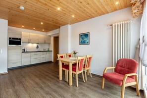 A modern kitchen with wooden cabinets and a dining area with a table and chairs. - Apartment 'Stübenwasen' with Balcony and Wi-Fi (Todtnau)