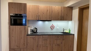 Une cuisine moderne avec des meubles en bois, un four encastré, une machine à café et un évier.
