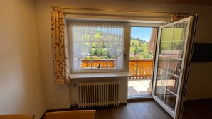 Une pièce avec une fenêtre donnant sur un balcon, un radiateur et un plafond en bois.