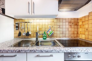 Eine Küche mit gefliestem Rücksprung, Edelstahlspüle und einem eingebauten Backofen.