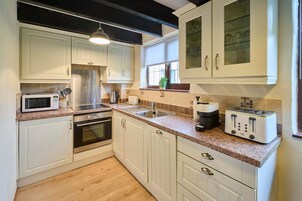 Una cocina moderna con armarios blancos, un refrigerador de acero inoxidable, un microondas, un tostador y un fregadero.