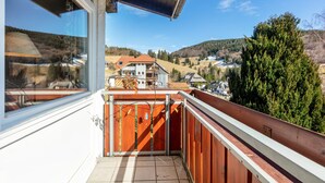 A balcony with a view of a village, a wooden fence, and a clear sky. - Apartment Hedi, 35 sqm with Mountain View, Balcony and Wi-Fi (Todtnau)