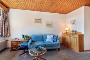 A living room with a blue sofa, wooden cabinet, and a small table with a bowl.