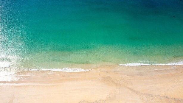 Een strand met helder turquoise water en een zandstrand.