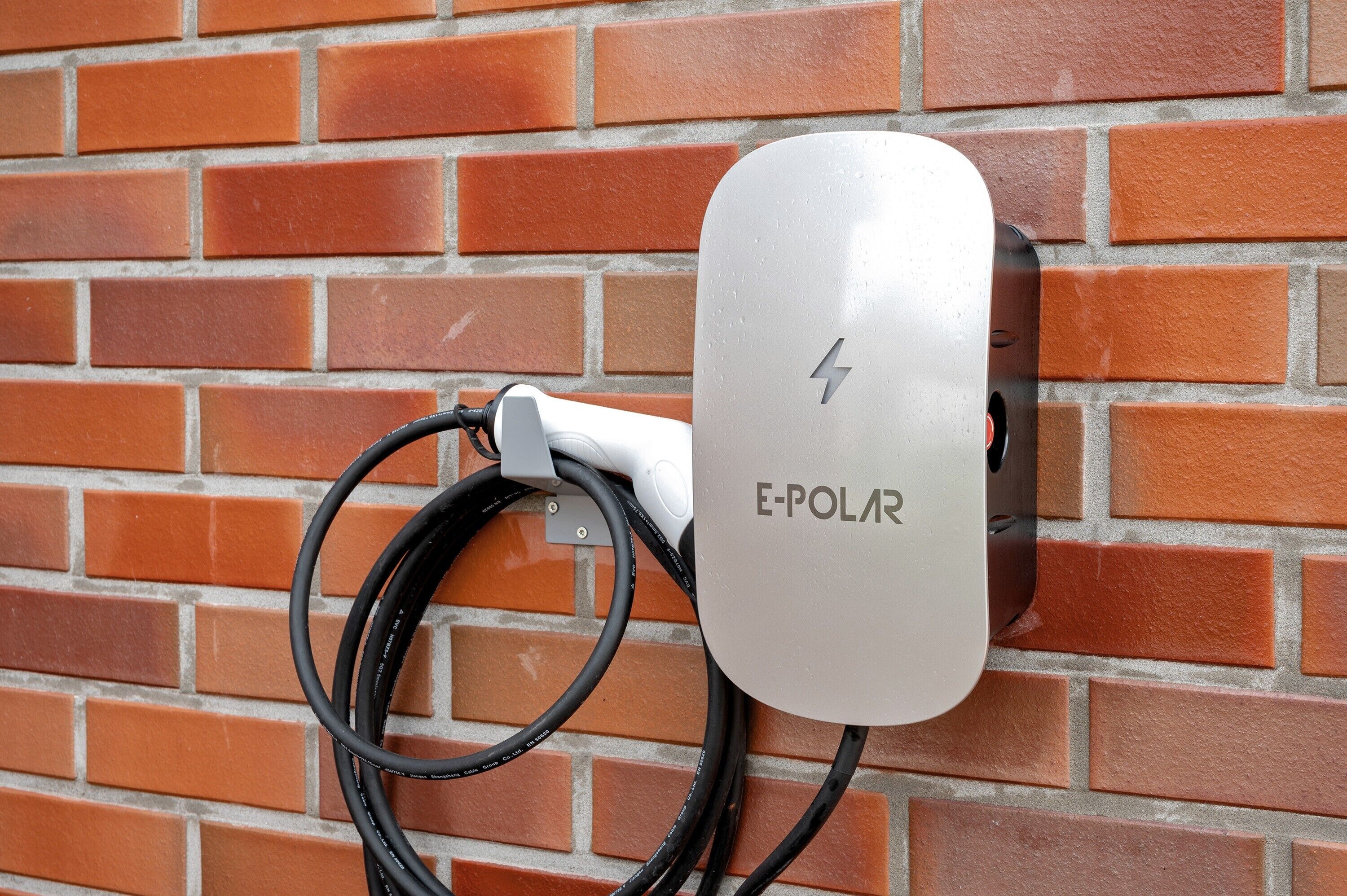 Une borne de recharge E-Polar fixée à un mur en briques.