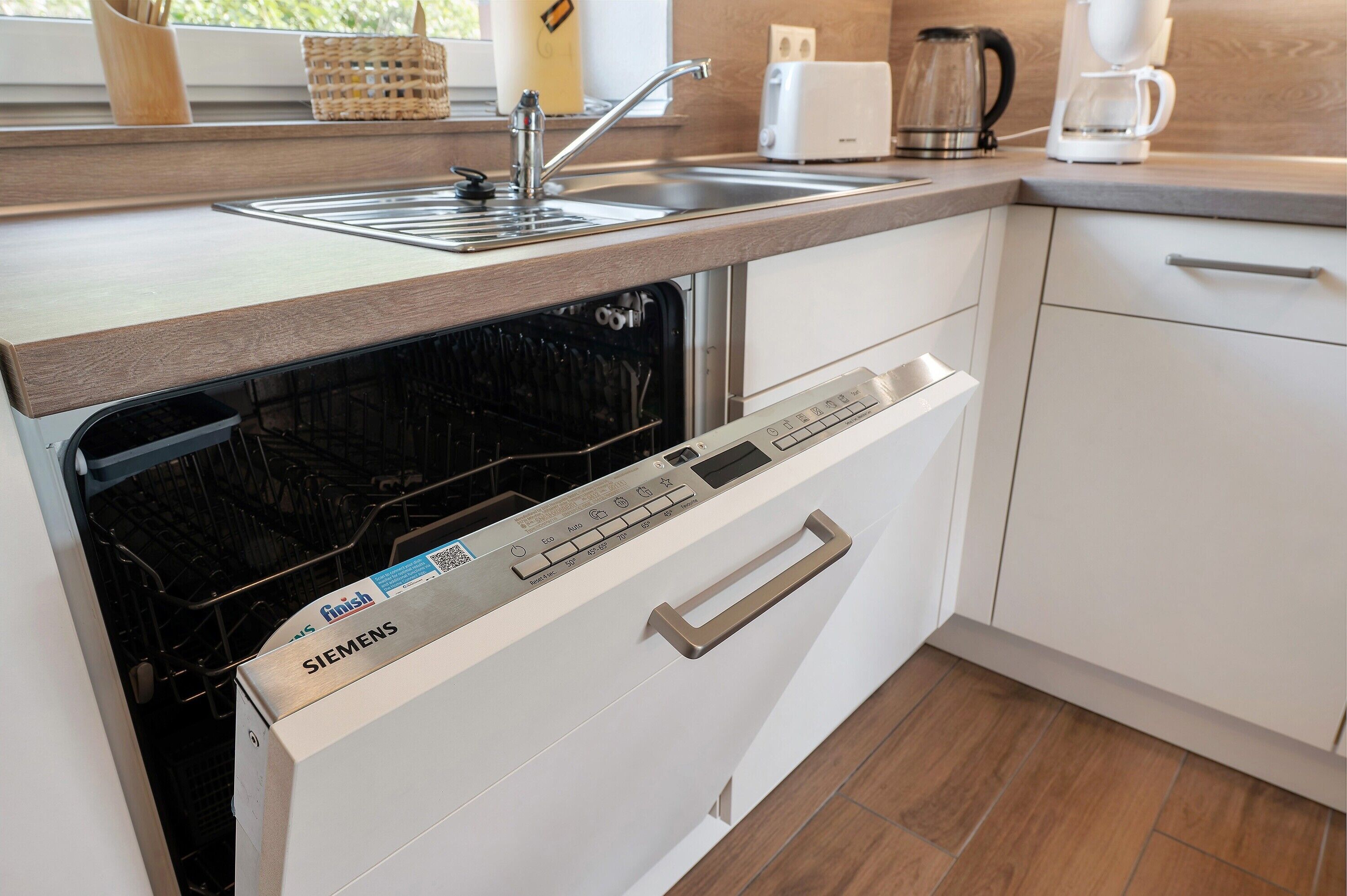 A kitchen with a dishwasher, a sink, a toaster, and a coffee maker.