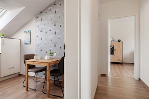 A modern kitchen with a wooden table, chairs, and a refrigerator. - Holiday Apartment 'Anna 1 Og' with Balcony (Suhle)