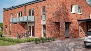 Ein modernes Ziegelgebäude mit überdachter Terrasse, Carport und Garage.