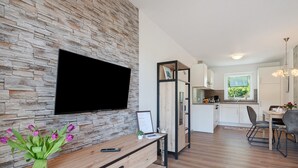 A modern living room with a flat-screen TV, a wooden coffee table, and a vase of flowers. - Holiday Apartment 'Anna 2 Eg' with Private Terrace and Garden (Suhle)