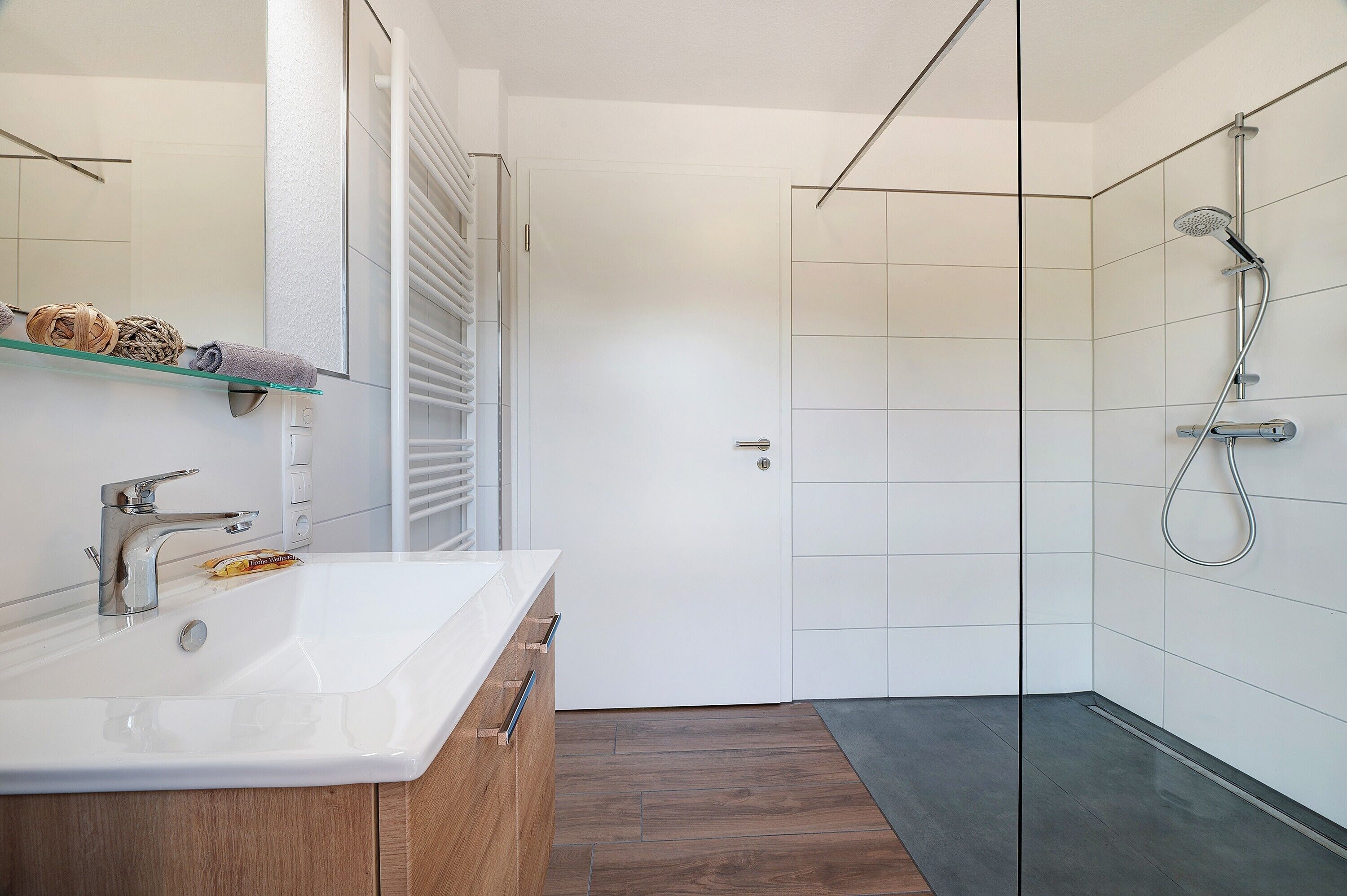 A modern bathroom with a white sink, mirror, and shower.