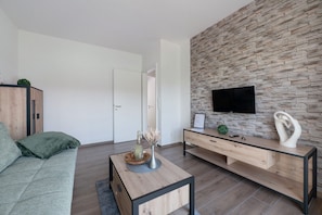 En moderne stue med en stenvæg, et fladskærms-tv, et træsofabord og en sofa.