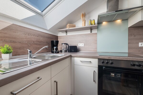 A modern kitchen with a skylight, stainless steel appliances, and wooden cabinetry.
