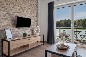 A modern room with a stone wall, a flat-screen TV, a wooden console table, and a balcony with outdoor furniture.