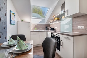 Et moderne køkken med ovenlys, et spiseområde med et bord dækket til to, og en menutavle monteret på væggen.