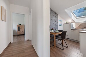 Una cucina moderna con un lucernario, pavimento in legno e zona pranzo con tavolo e sedie.