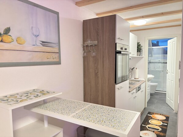 Une cuisine moderne avec des meubles en bois, un four encastré et un plan de travail agrémenté d’un crédence décorative.