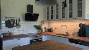 A modern kitchen with white cabinets, a wooden countertop, a built-in oven, and a Siemens dishwasher. - Vacation apartment in a cozy farmhouse by the bathing lake with large garden and sauna (Carpin)