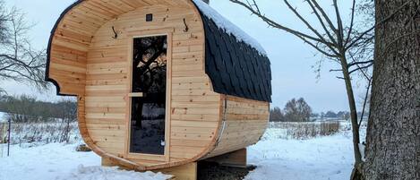 A wooden cabin with a curved roof, a door, and a chimney.