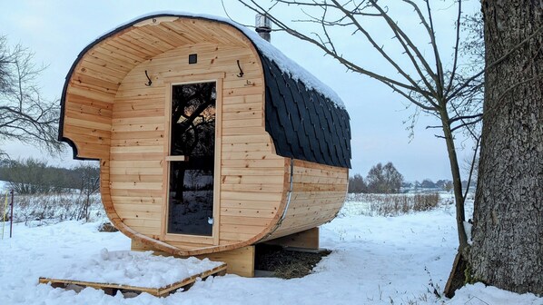 A wooden cabin with a curved roof, a door, and a chimney.