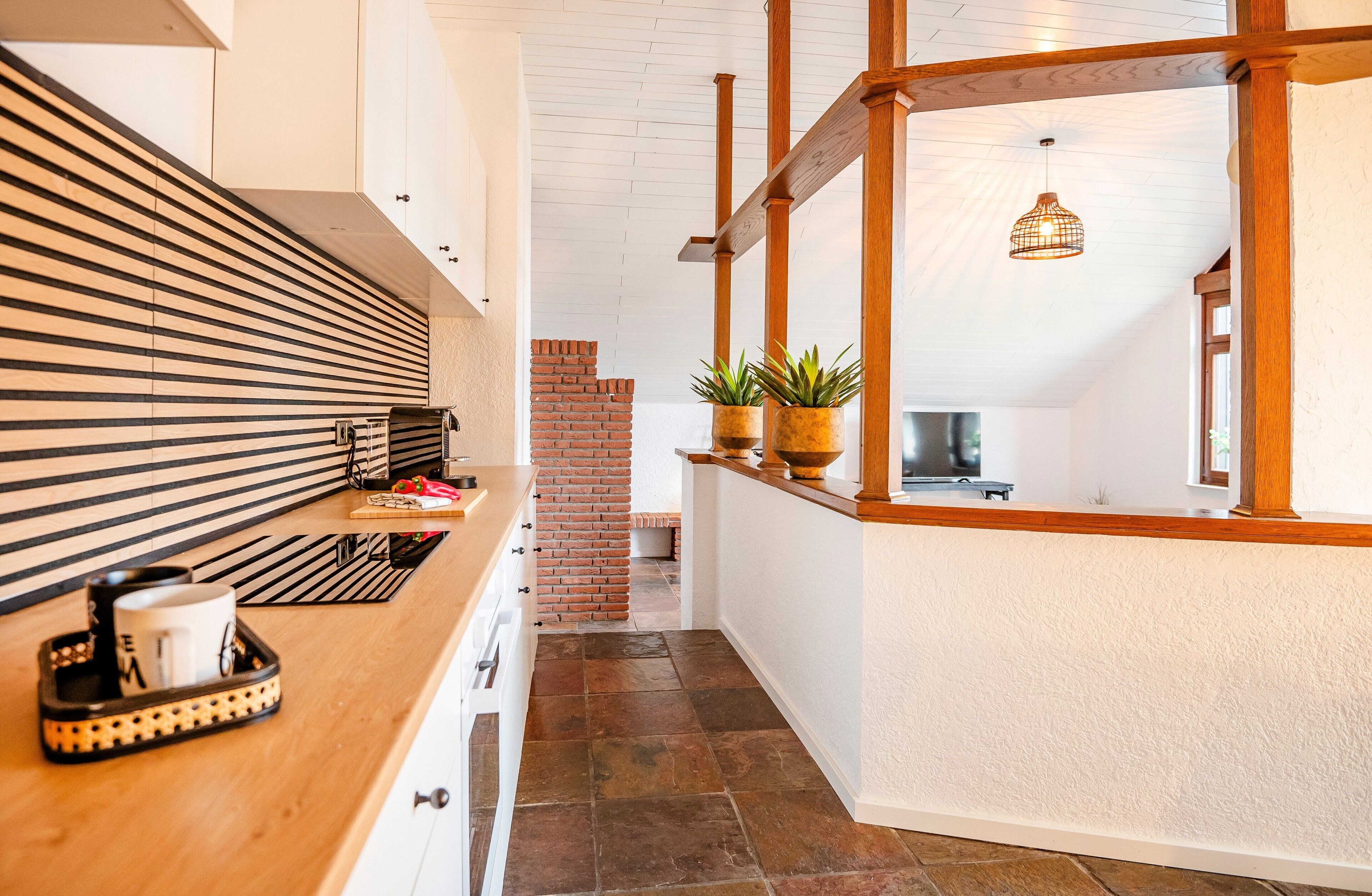 A narrow hallway with a wooden counter, a brick wall, and a hanging light fixture.