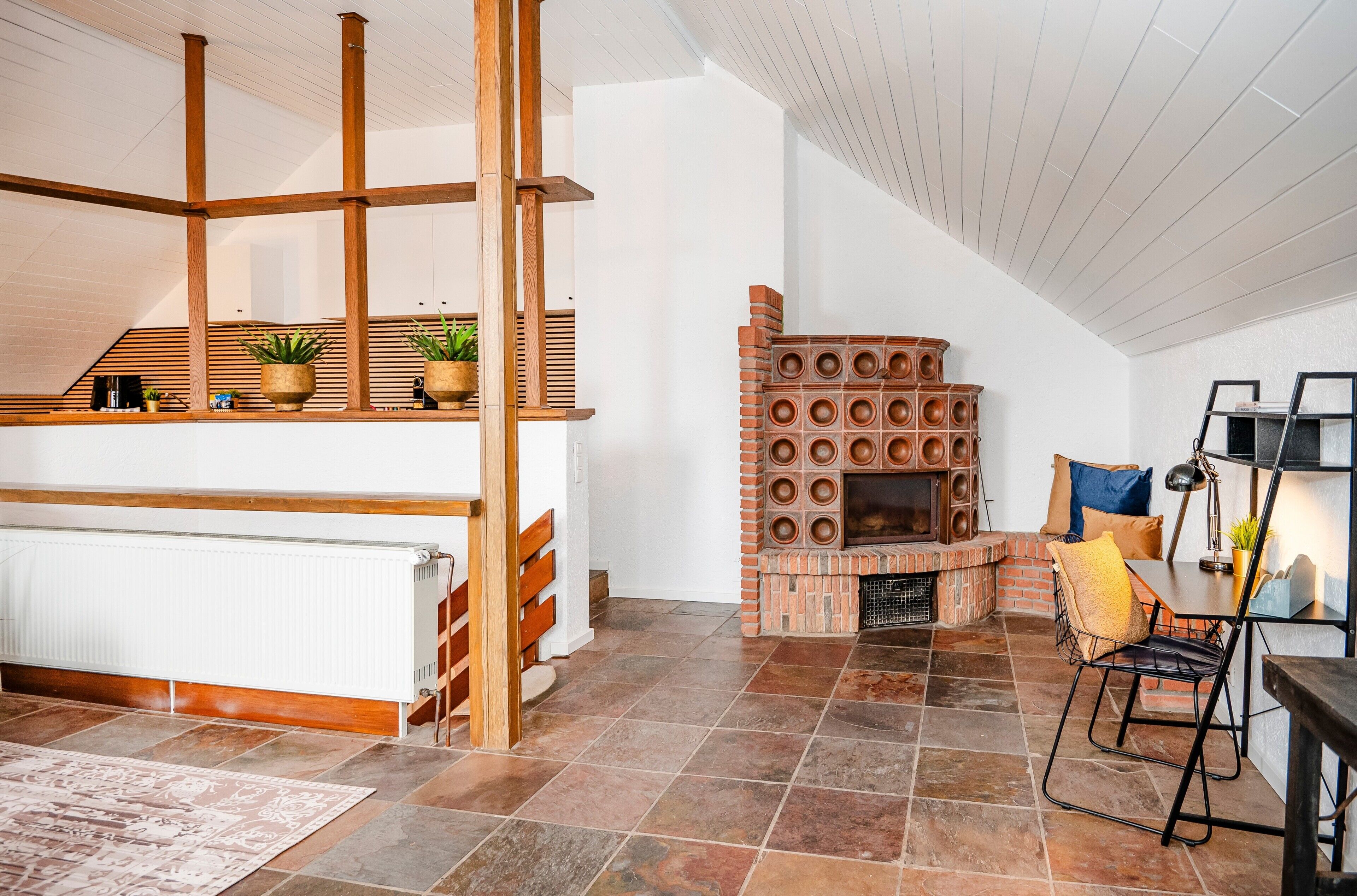 Un interior moderno con chimenea, vigas de madera y suelo de baldosas.