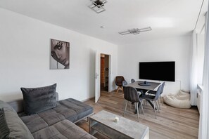 A modern living room with a grey sofa, a dining table with chairs, a flat-screen TV, and a wooden floor. - Apartment 'Schwanthalerhöhe' with Wi-Fi (München)
