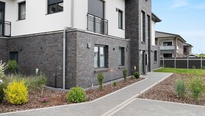 A modern two-story house with a brick facade, large windows, and a small balcony.