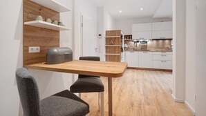 A modern kitchen with white cabinets, a wooden countertop, and a built-in shelf with kitchenware.