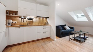 A modern kitchen with white cabinets, a wooden countertop, and a skylight.