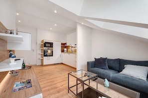 Un apartamento moderno con cocina, sala de estar con sofá y una mesa de centro de vidrio.