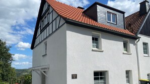 En vit byggnad med ett rött tegeltak, flera fönster och en skylt som visar att det är ett hotell.